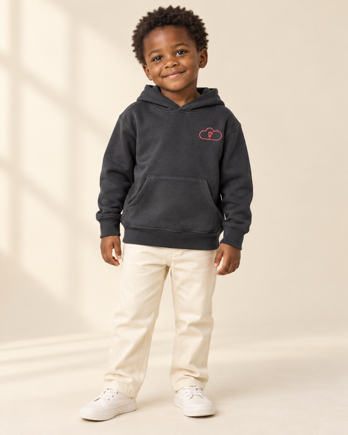 Child wearing a black Afternoon Blossom Hoodie with a pink cloud-and-rose chest emblem.