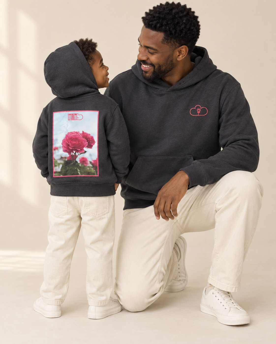 Father and child wearing matching black Afternoon Blossom Hoodies with rose artwork.
