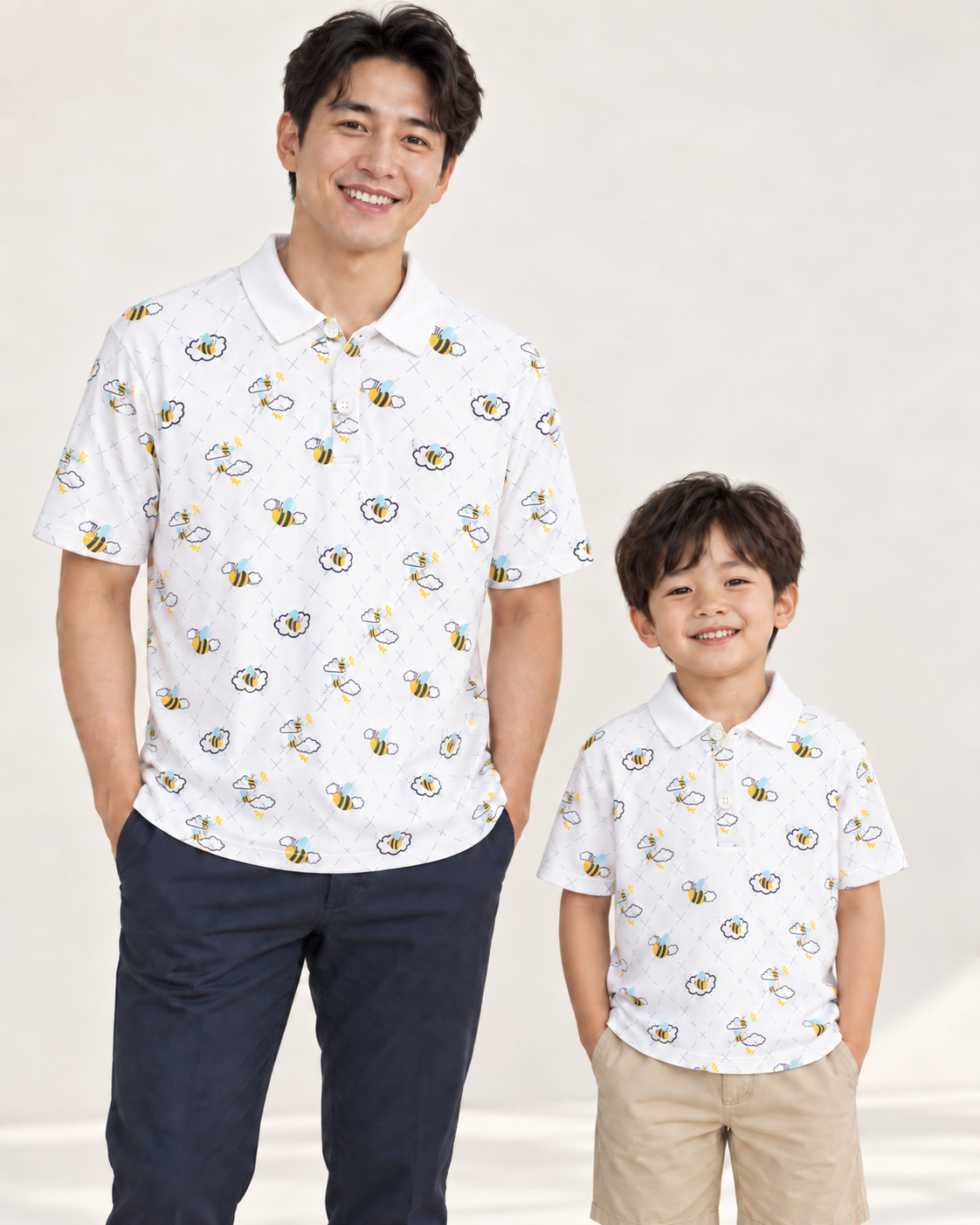 Father and child wearing matching white Buzzed Polos with a bee-and-cloud print.