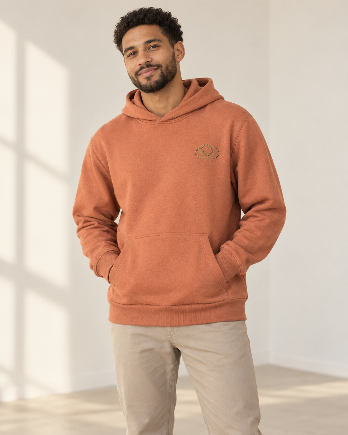 Father wearing a terracotta Hunted Hoodie with a green cloud-and-antler chest emblem.